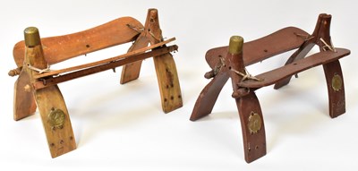 Lot 300 - Two Arabic wooden camel saddle stands, with...