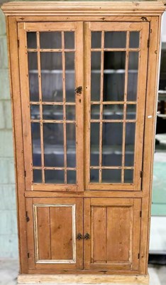 Lot 683 - A pine cupboard with a pair of glazed upper...