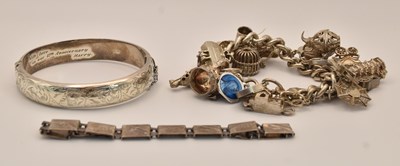 Lot 1433 - A silver charm bracelet, with charms including...