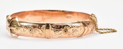 Lot 65 - A 9ct rose gold buckle hinged snap bangle,...