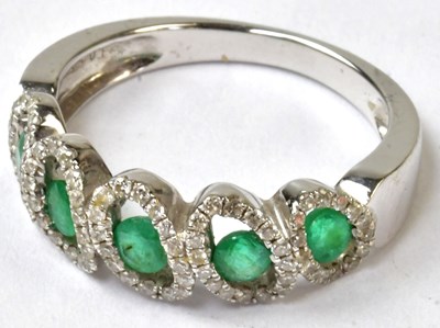 Lot 870 - A 14ct white gold ring set with five emeralds,...