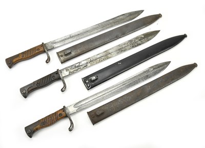 Lot 1057 - A group of three sawback bayonets, blades...
