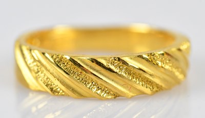 Lot 431 - A yellow metal textured band ring, impressed...
