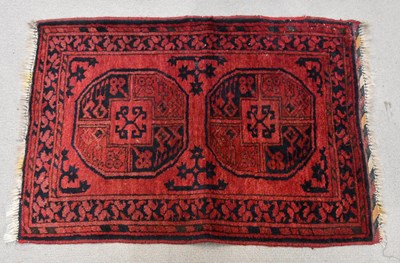 Lot 188 - A small red ground rug, with two circular...