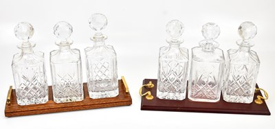 Lot 1465 - Two sets of three cut glass decanters on...