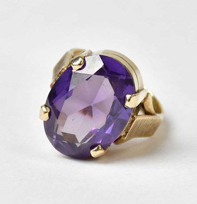 Lot A 9ct yellow gold ring set with an oval purple...