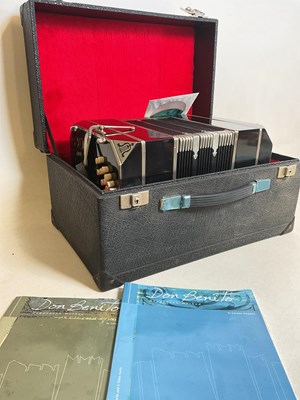 Lot 599 - A cased accordion with music booklets.