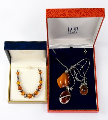 Lot 1268 - Two amber-coloured pendants, one an irregular...