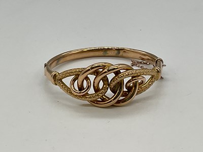 Lot 1166 - An Edwardian 9ct yellow gold hinged bangle...