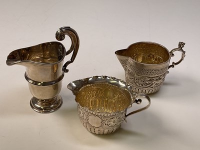 Lot 1051 - Three small hallmarked silver cream jugs; John...