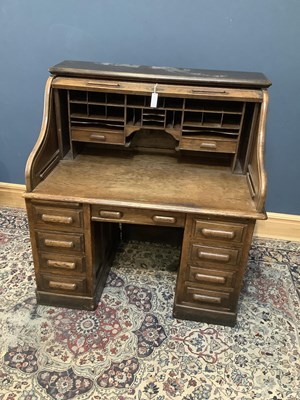 Lot 2446 - a late 19th century oak kneehole roll top desk,...