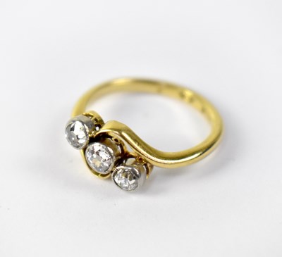 Lot 1003 - An 18ct gold three-stone diamond cross-over ring