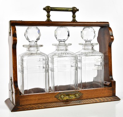 Lot 1344 - A 1920s oak and brass mounted tantalus, the...