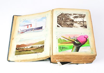 Lot 605 - A postcard album with coloured and black and...