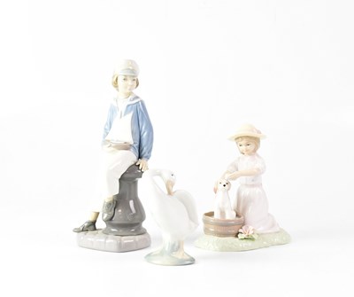 Lot 590 - LLADRÓ; a figure of a seated young boy holding...