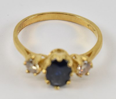 Lot 899 - An 18ct yellow gold ring set with central blue...