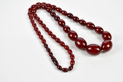 Lot 380 - A strand of cherry amber coloured beads,...