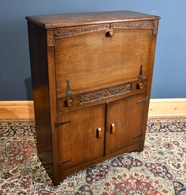 Lot 1179 - A 1930s carved oak secretaire, with fall front...