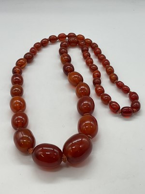 Lot 1233 - A caramel amber graduated oval bead necklace,...