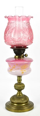 Lot 1558 - An early 20th century oil lamp with cranberry...