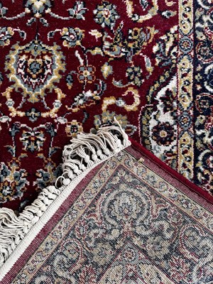Lot 97 - A red ground floral decorated rug with blue...