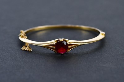 Lot 270 - A yellow metal ruby hinged snap bangle, the...