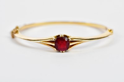 Lot 404 - A yellow metal hinged snap bangle, set with a...
