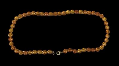 Lot 1493 - A single strand of amber coloured beads with a...
