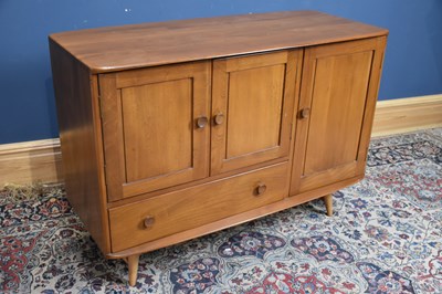 Lot 1154 - ERCOL; a medium elm sideboard with three doors...