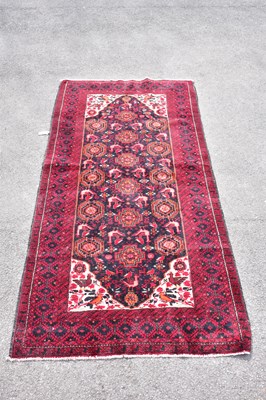 Lot 445 - A red ground wool carpet with geometric...