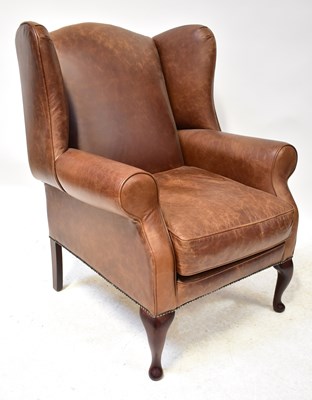 Lot 13 - A modern brown leather wing armchair with...