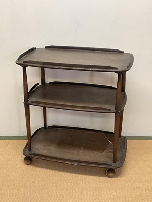 Lot 694 - ERCOL; a dark stained three tier trolley on...