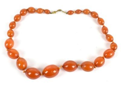 Lot 279 - A graduated row of oval amber coloured beads...