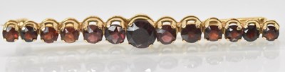 Lot 1245 - An 18ct yellow gold garnet set bar brooch, the...