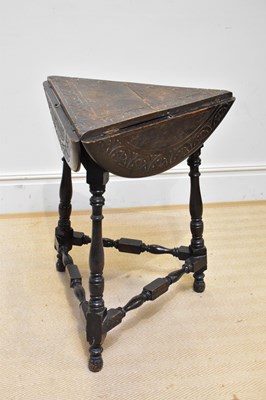 Lot 1293 - A carved oak triangular shaped drop-leaf table,...