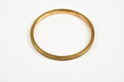 Lot 421 - A 9ct yellow gold bangle with engine turned...
