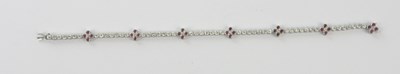 Lot 412 - A white metal diamond and ruby line bracelet,...