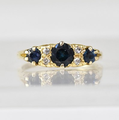 Lot 1085 - An 18ct gold three-stone sapphire and diamond...
