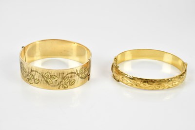 Lot 498 - Two rolled gold bangles with engraved decoration.